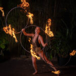 a photo of a woman spinning flaming hoops during the fire show