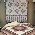 a beautiful gray and white start quilt hanging over a bed with a lonestar quilt on it